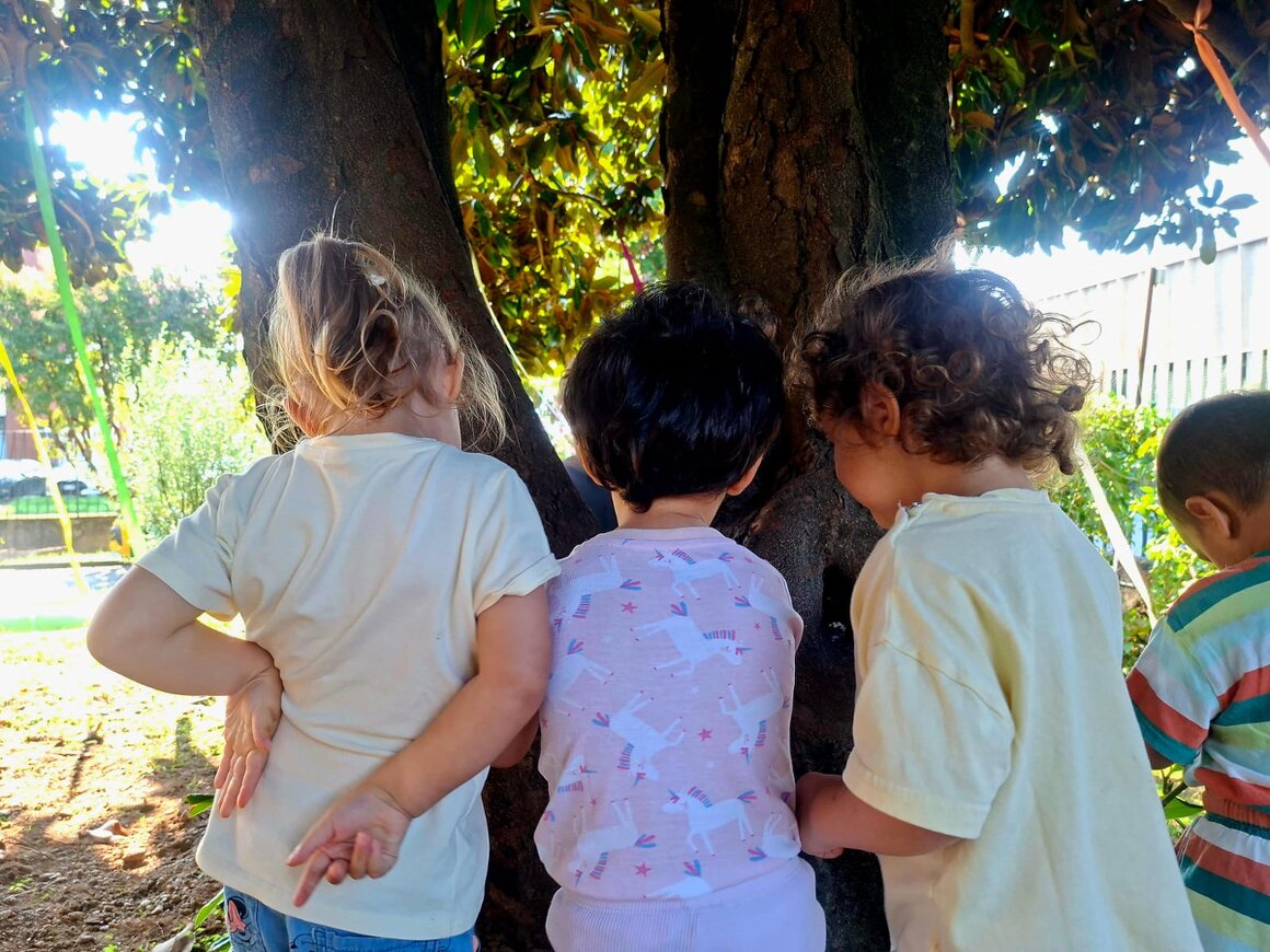 Bambini piccoli che sfogliano libri cartonati con un’educatrice
