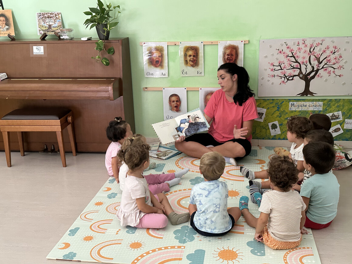 Educatrice che legge un libro ad alta voce a un gruppo di bambini
