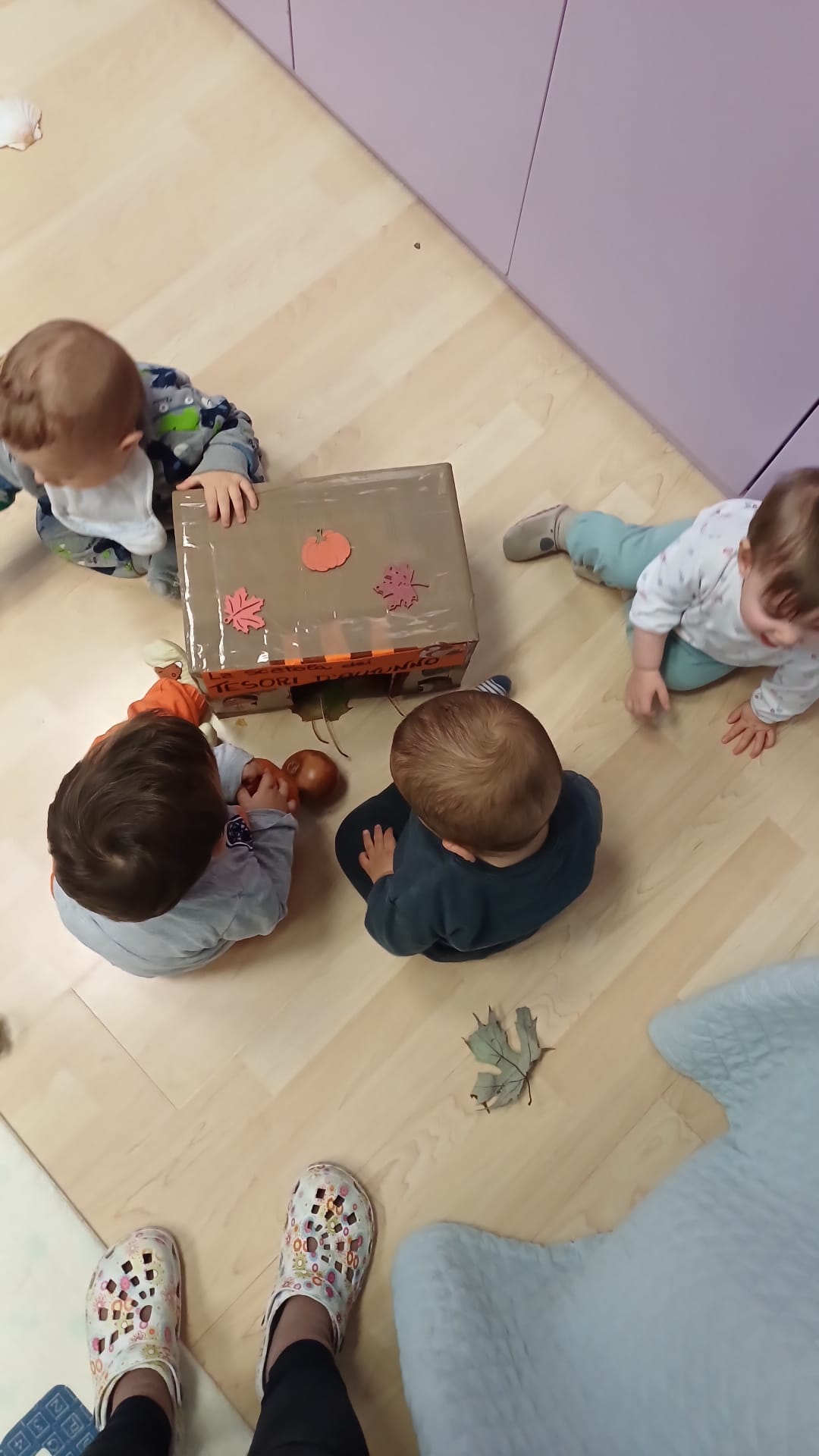 Piccolo gruppo di bambini molto piccoli con educatrice in uno spazio morbido
